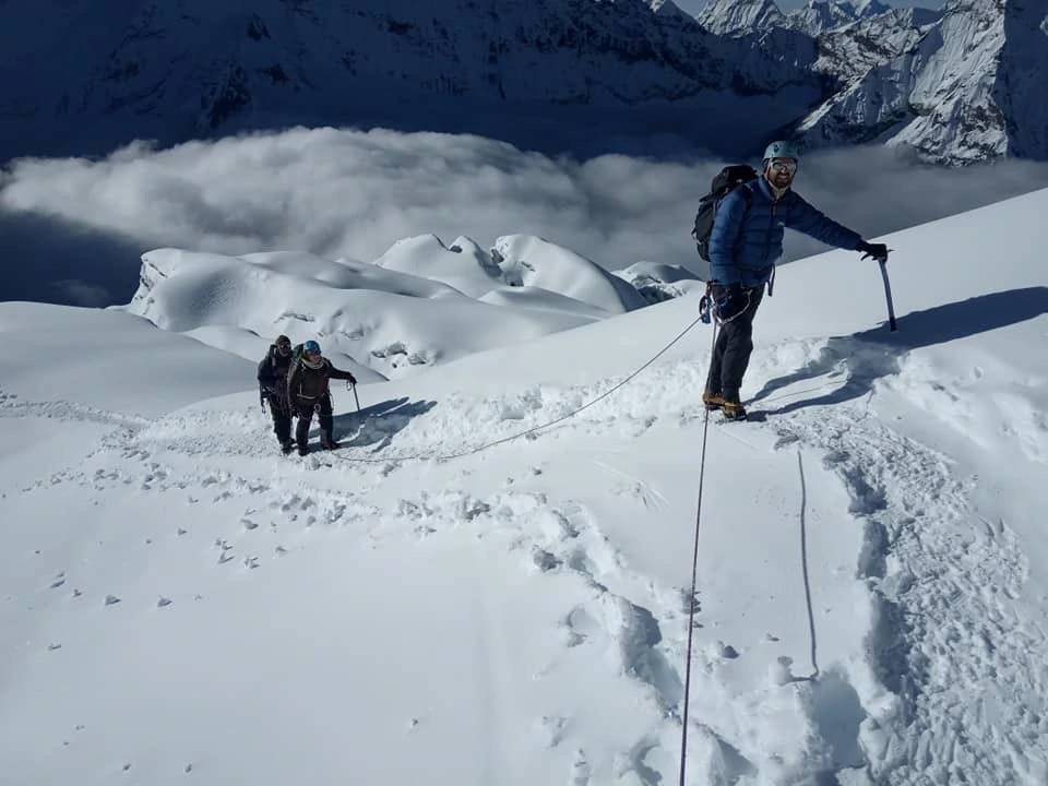 Mountaineers using ladder to cross glacier crevasse on Island Peak expedition in Nepal